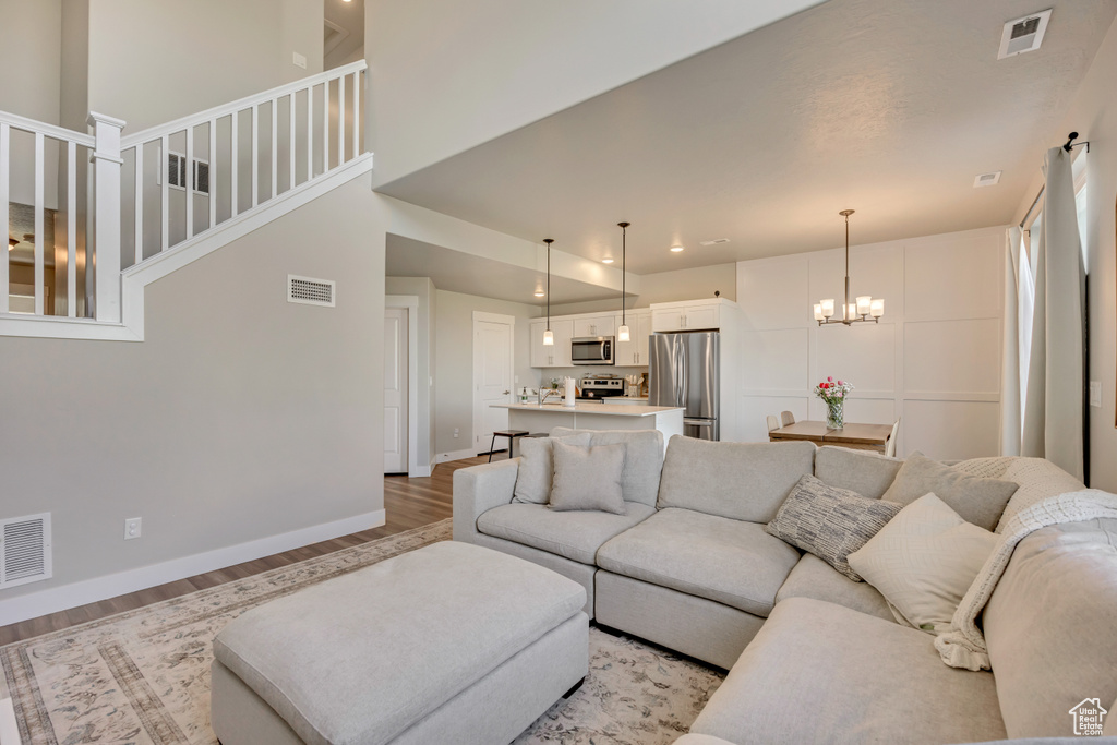 Living area with light wood-type flooring, stairway, baseboards, a chandelier, and recessed lighting
