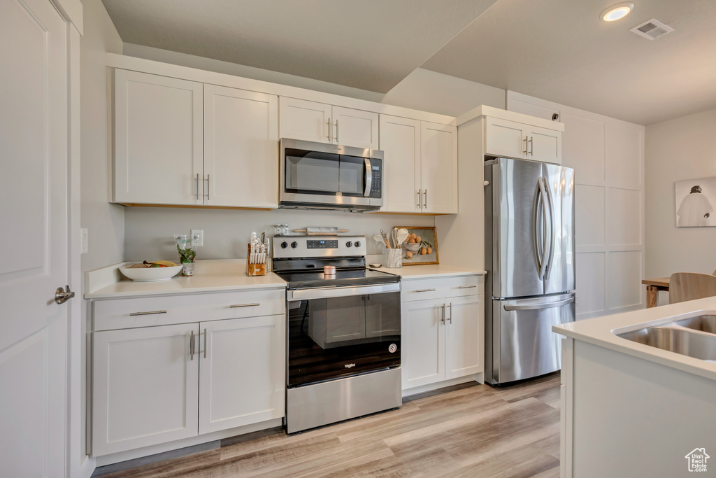 Kitchen with appliances with stainless steel finishes, white cabinetry, light countertops, and recessed lighting