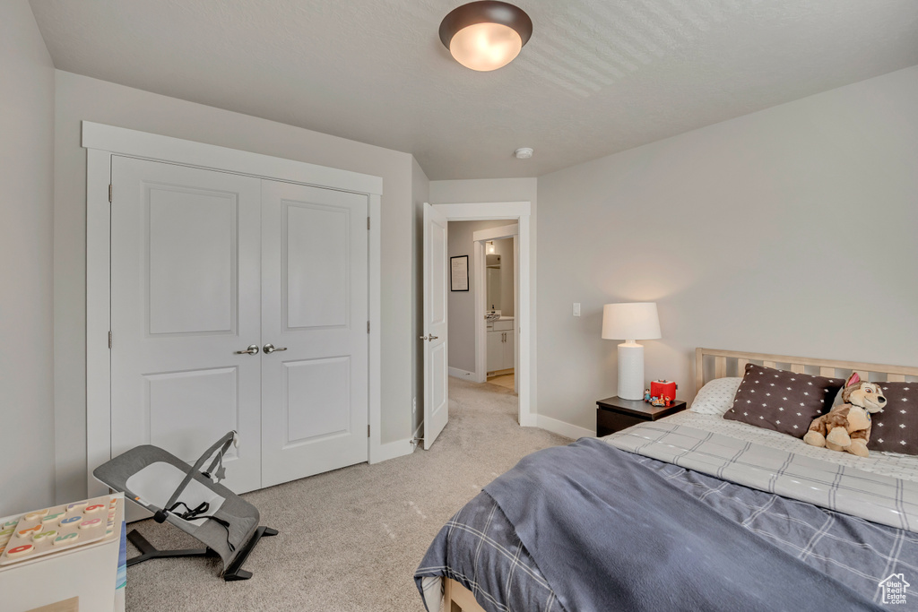 Bedroom featuring light carpet, baseboards, and a closet