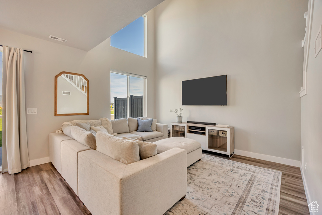 Living room featuring baseboards, wood finished floors, and a high ceiling
