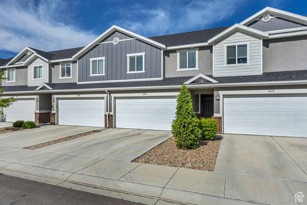 Townhome / multi-family property featuring an attached garage, brick siding, and concrete driveway