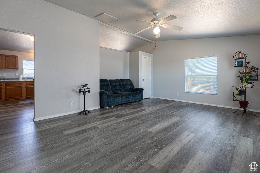 Unfurnished room with a ceiling fan, dark wood finished floors, a textured ceiling, baseboards, and vaulted ceiling