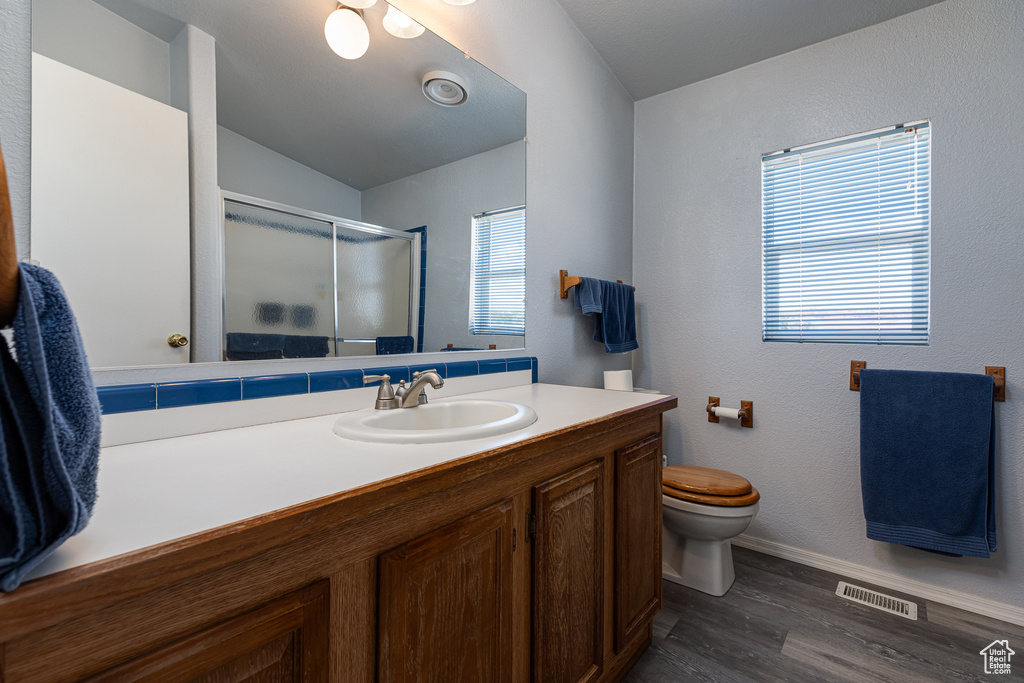 Full bathroom featuring a shower stall, vanity, wood finished floors, toilet, and baseboards