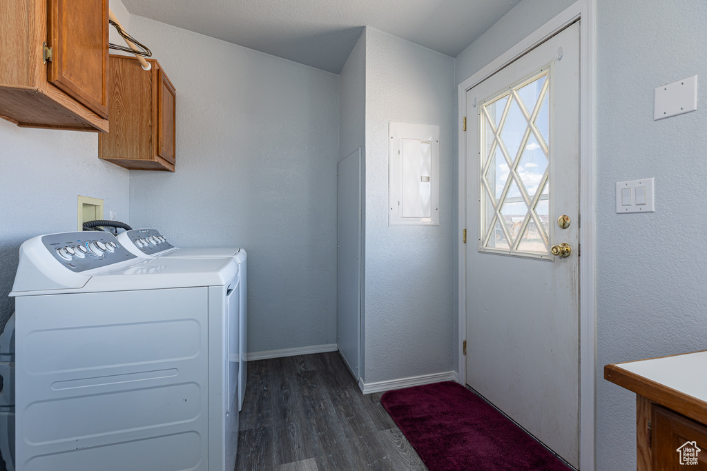 Laundry area with cabinet space, dark wood finished floors, separate washer and dryer, electric panel, and baseboards