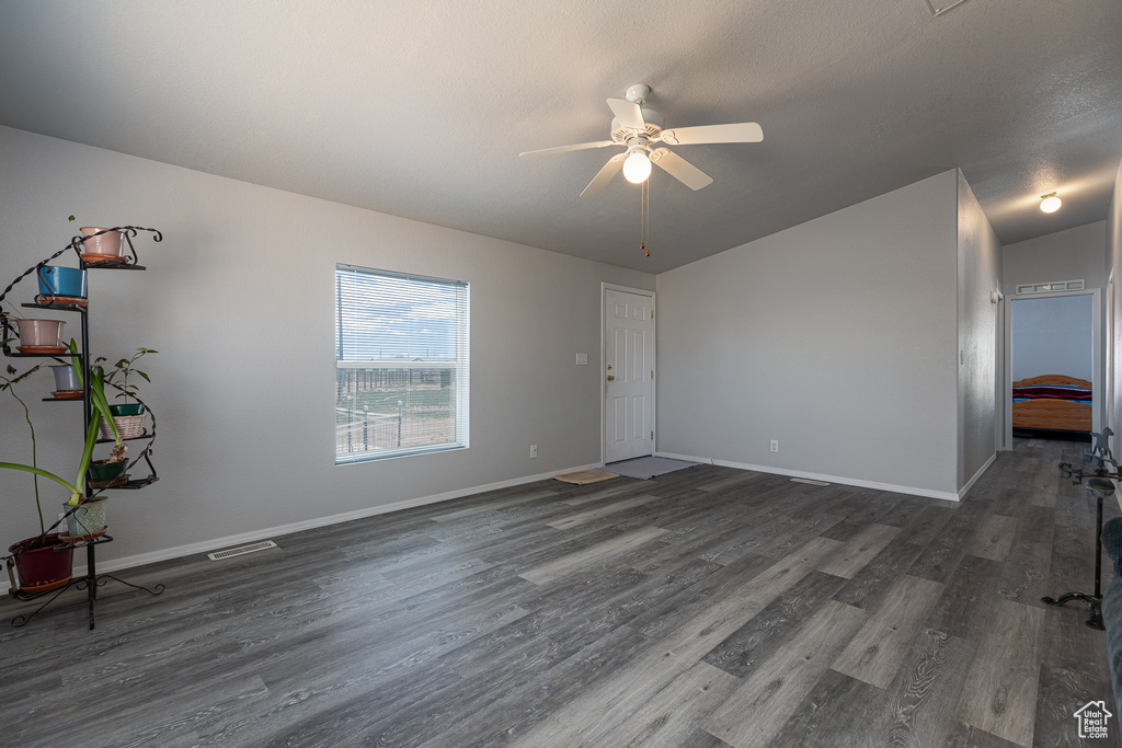 Unfurnished living room with a ceiling fan, dark wood-style floors, and baseboards