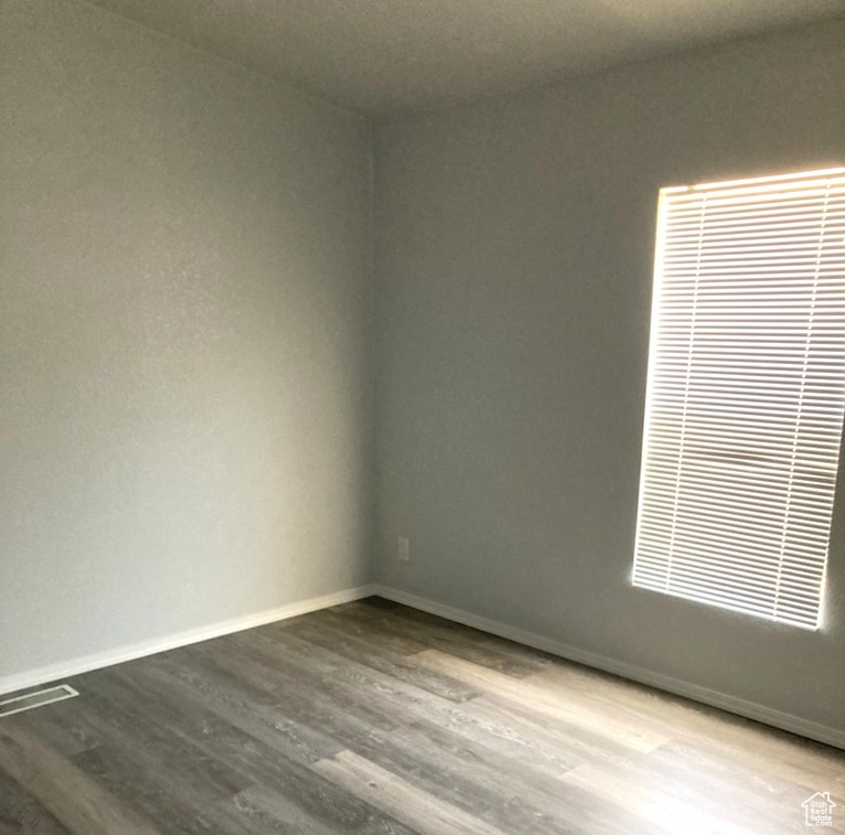 Spare room with dark wood-style floors and baseboards