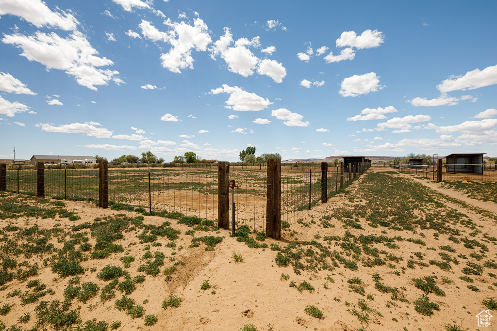 View of yard featuring a view of rural / pastoral area, fence, an outbuilding, and an exterior structure
