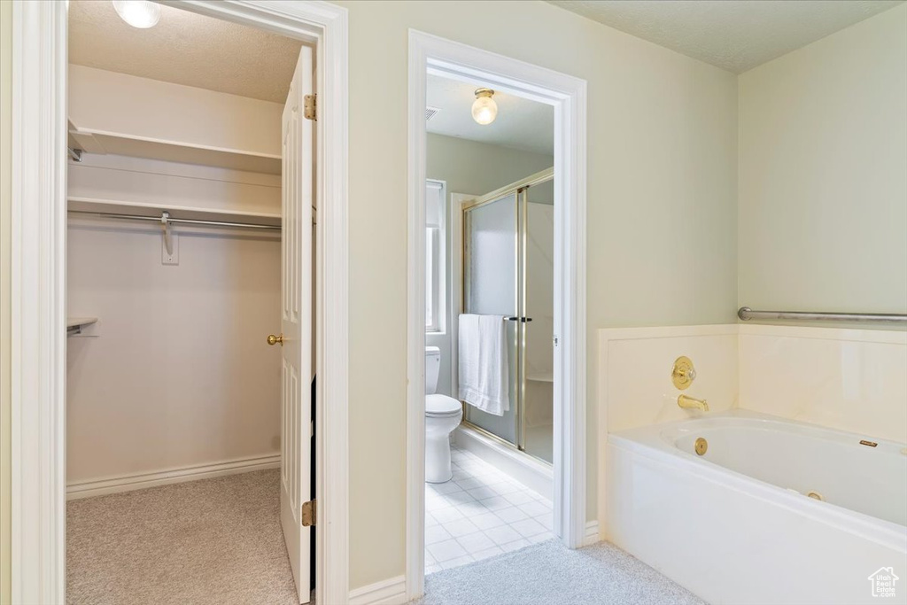 Bathroom featuring a stall shower, toilet, a bath, and a walk in closet