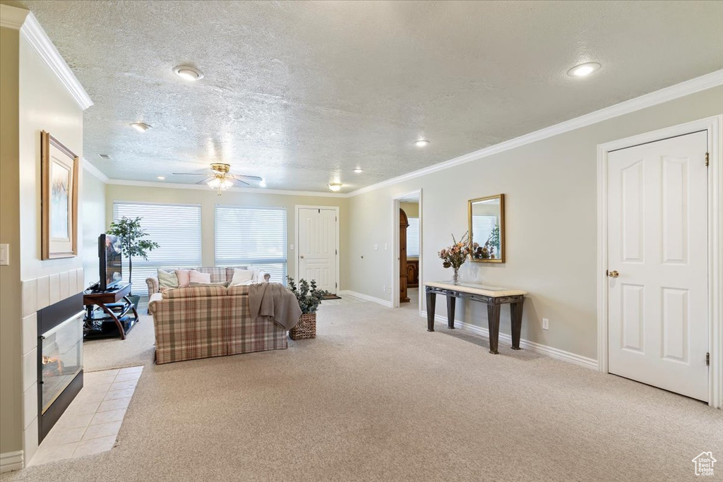 Carpeted living room featuring a ceiling fan, recessed lighting, crown molding, baseboards, and a textured ceiling