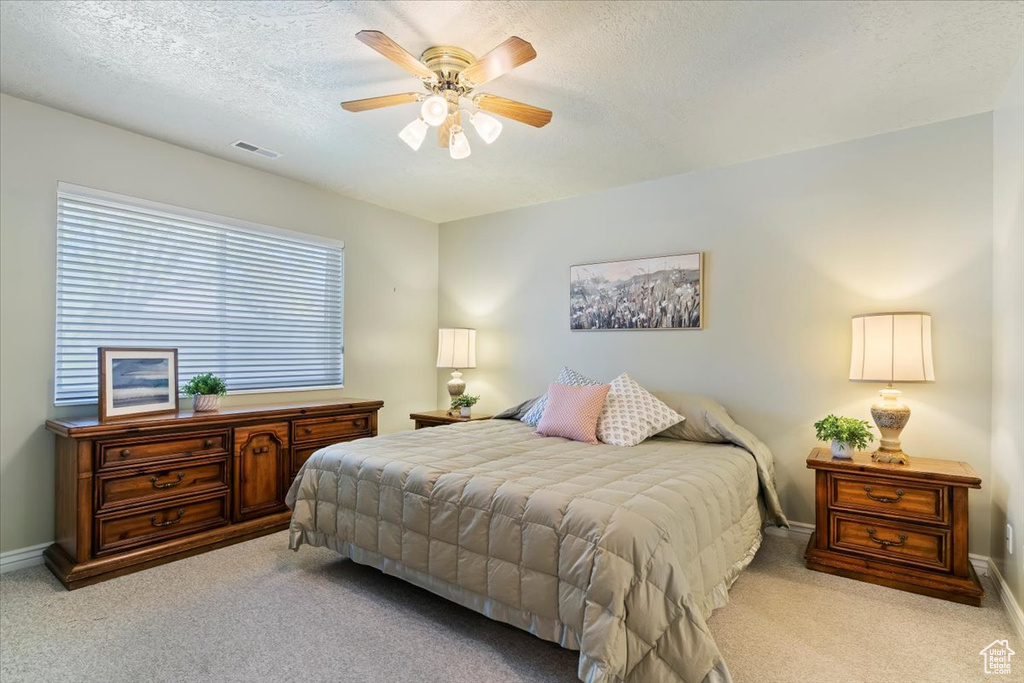 Carpeted bedroom featuring baseboards, a textured ceiling, and a ceiling fan