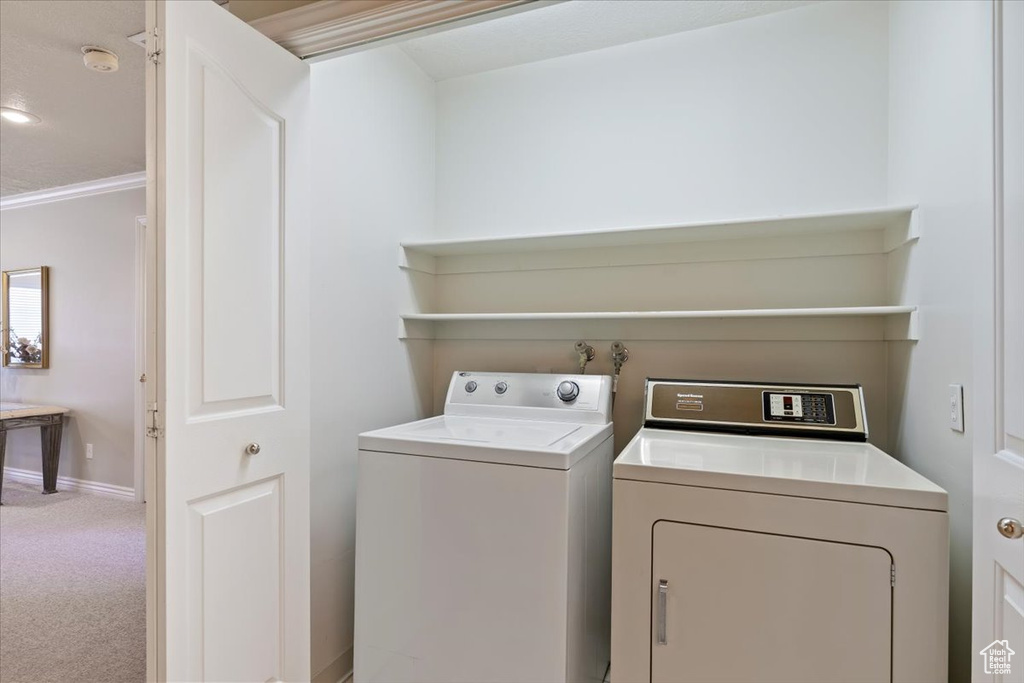 Clothes washing area featuring independent washer and dryer, carpet flooring, baseboards, and crown molding