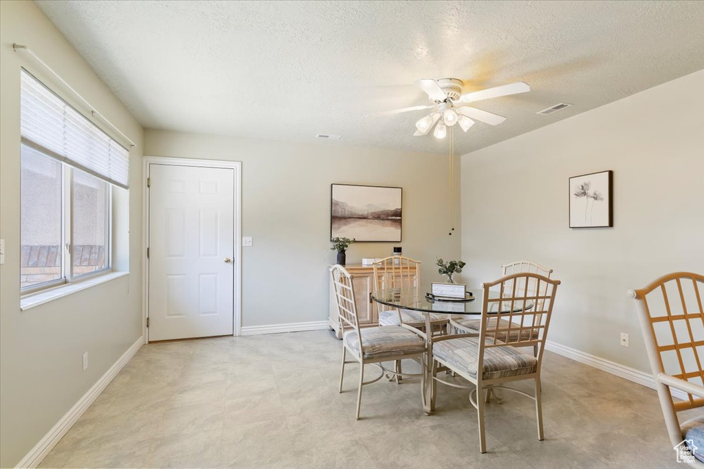 Dining room featuring a ceiling fan, a textured ceiling, and baseboards