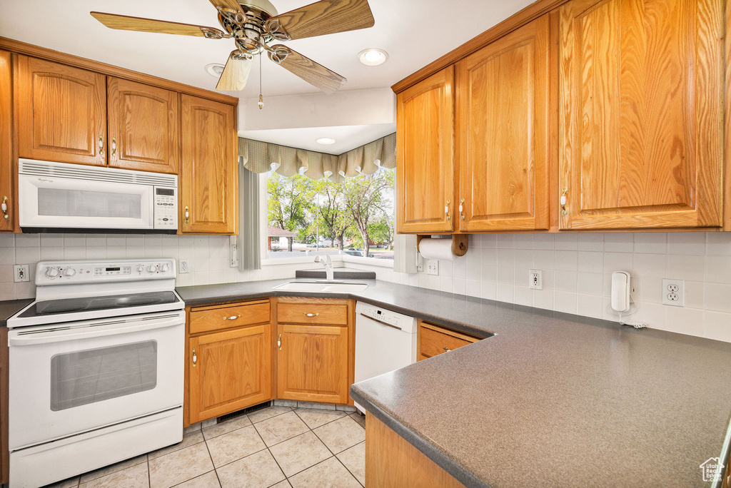 Kitchen featuring white appliances, a sink, dark countertops, backsplash, and recessed lighting