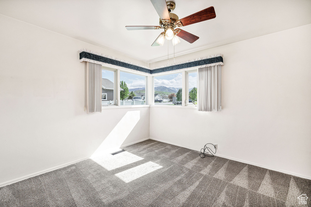 Carpeted empty room featuring a ceiling fan and baseboards