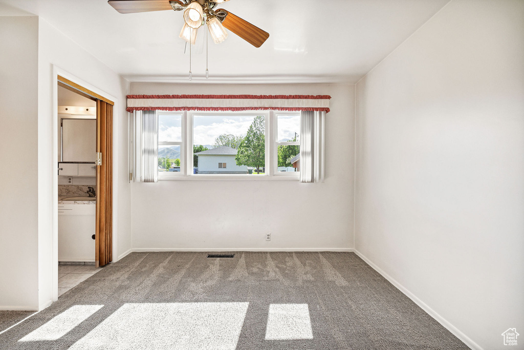 Spare room featuring carpet floors, ceiling fan, and baseboards