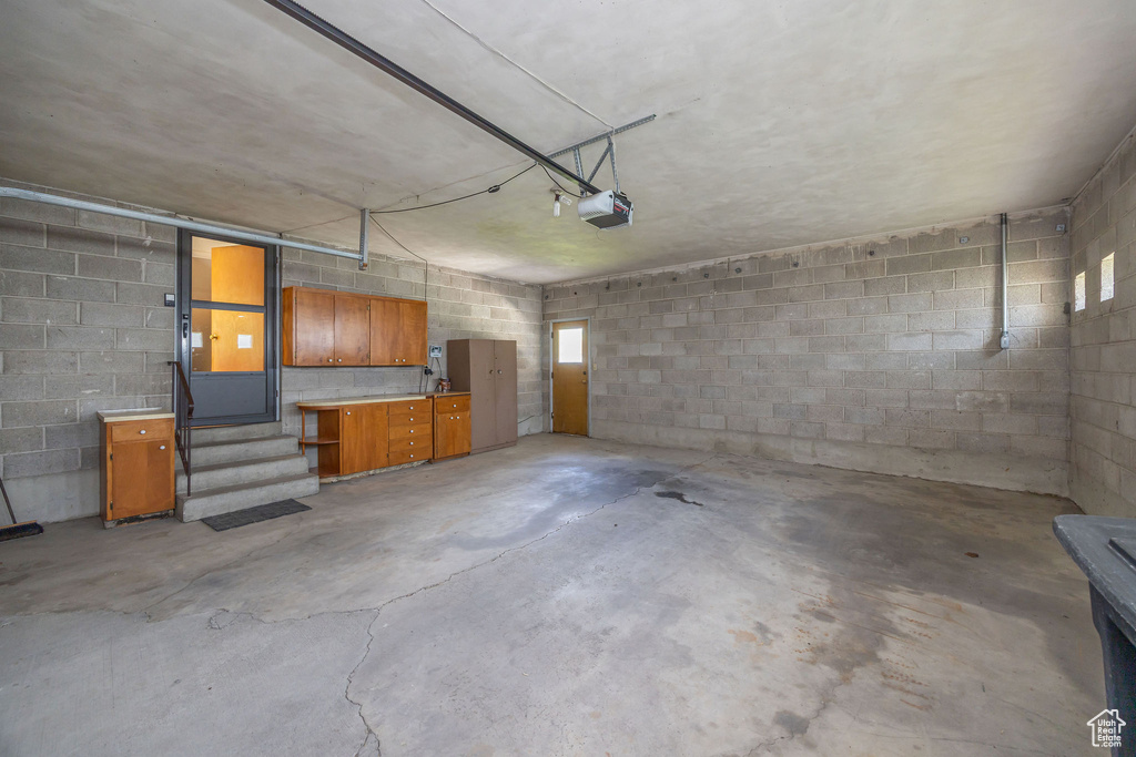 Garage featuring a garage door opener and concrete block wall