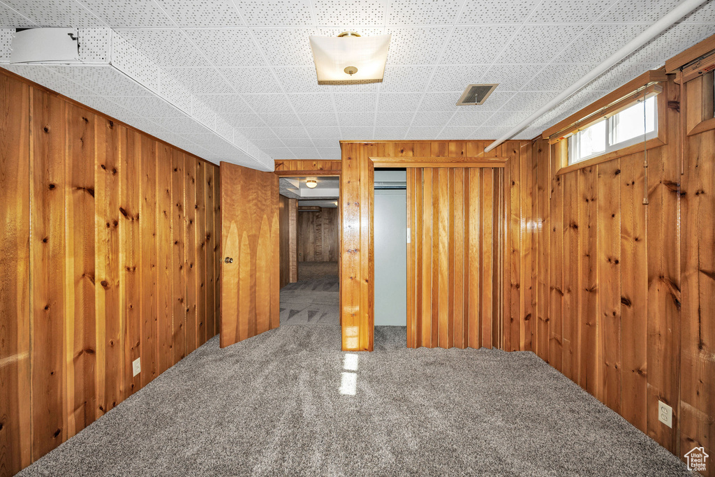 Carpeted empty room featuring wood walls