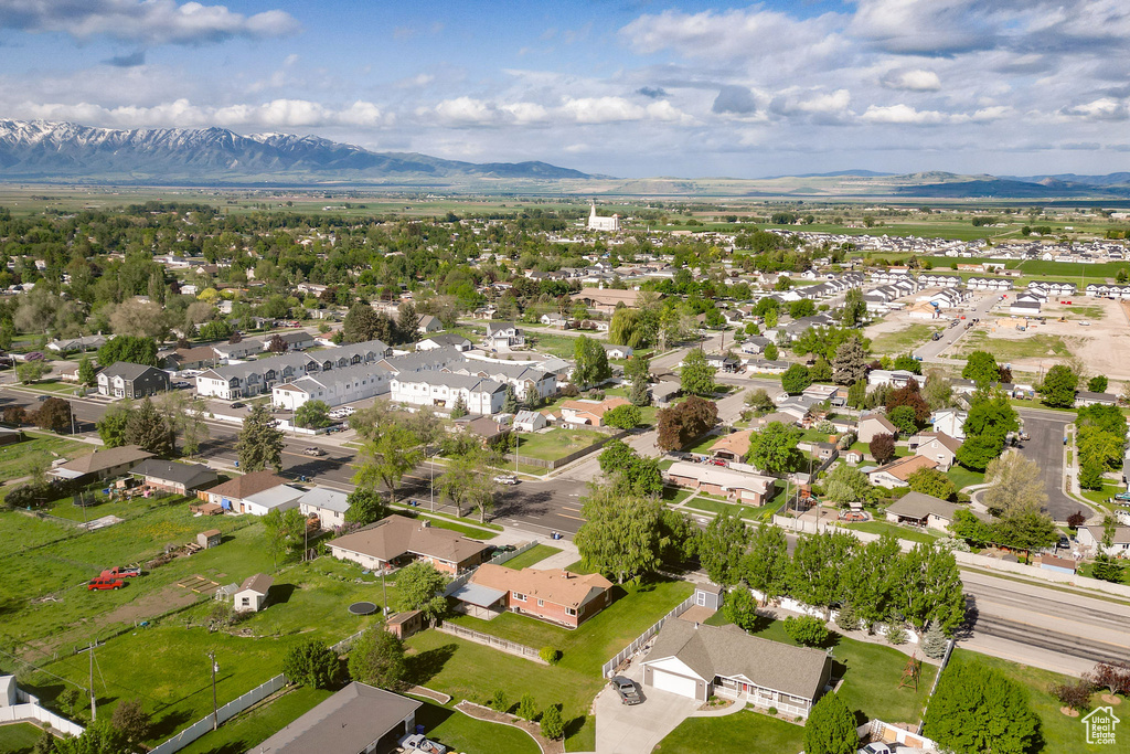 Aerial view of property and surrounding area featuring a mountain backdrop and nearby suburban area