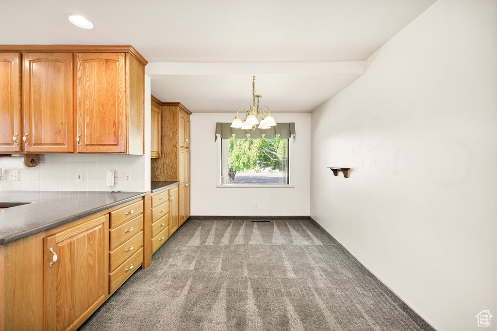 Kitchen with carpet floors, a chandelier, backsplash, dark countertops, and decorative light fixtures