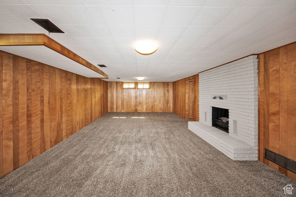 Below grade area with carpet, wooden walls, and a fireplace