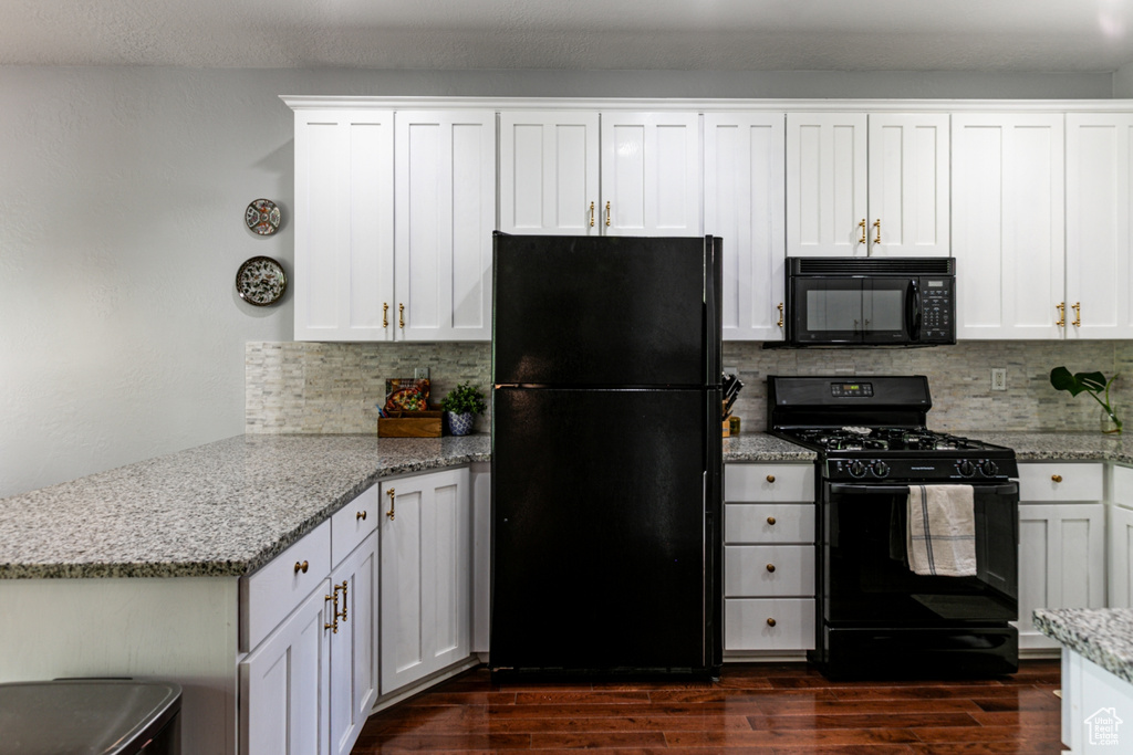 Kitchen featuring black appliances, a peninsula, decorative backsplash, dark wood-style flooring, and white cabinets