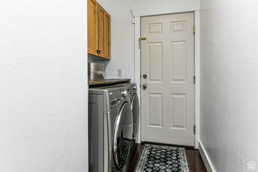 Clothes washing area with cabinet space, washer and dryer, dark wood finished floors, baseboards, and a textured wall