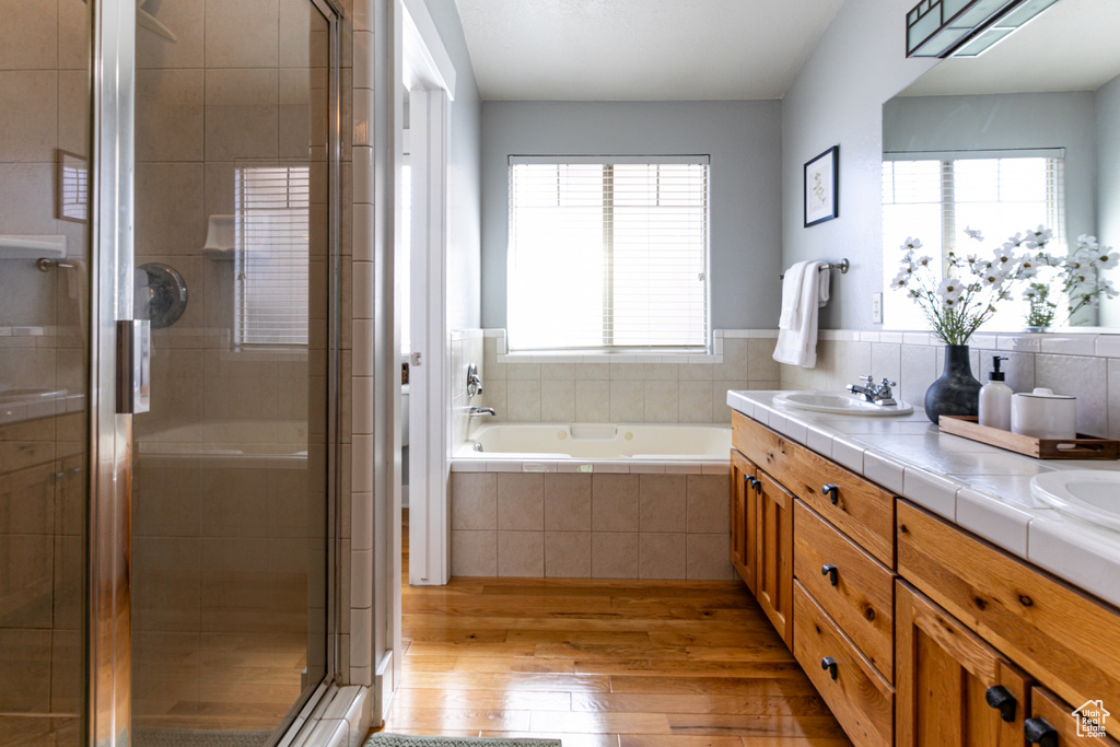 Full bath with hardwood / wood-style floors, healthy amount of natural light, a shower stall, and a garden tub