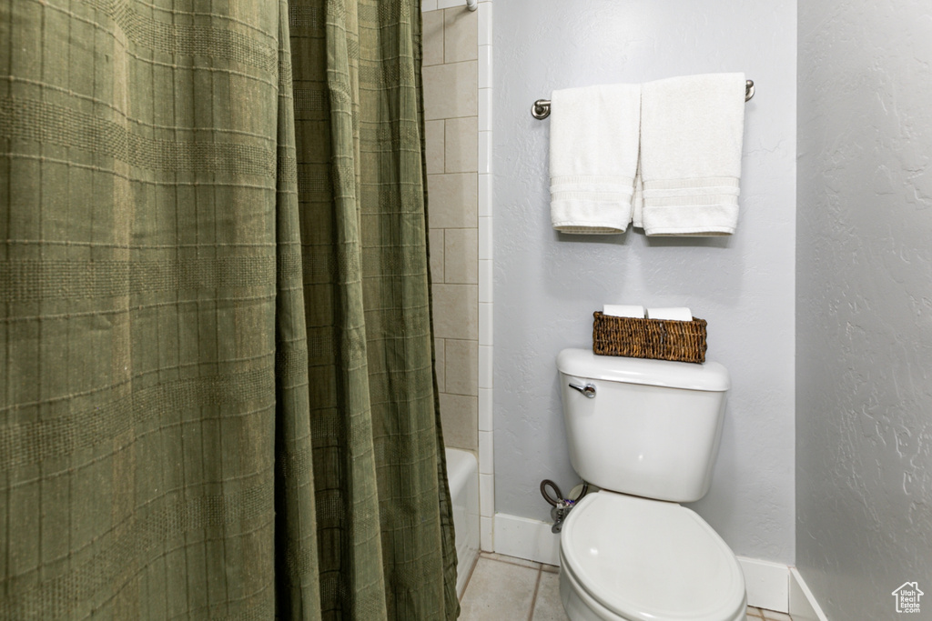 Bathroom featuring baseboards, toilet, and tile patterned floors