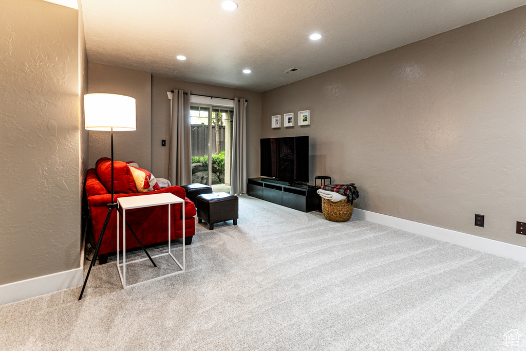 Living area with carpet floors, a textured wall, recessed lighting, and baseboards