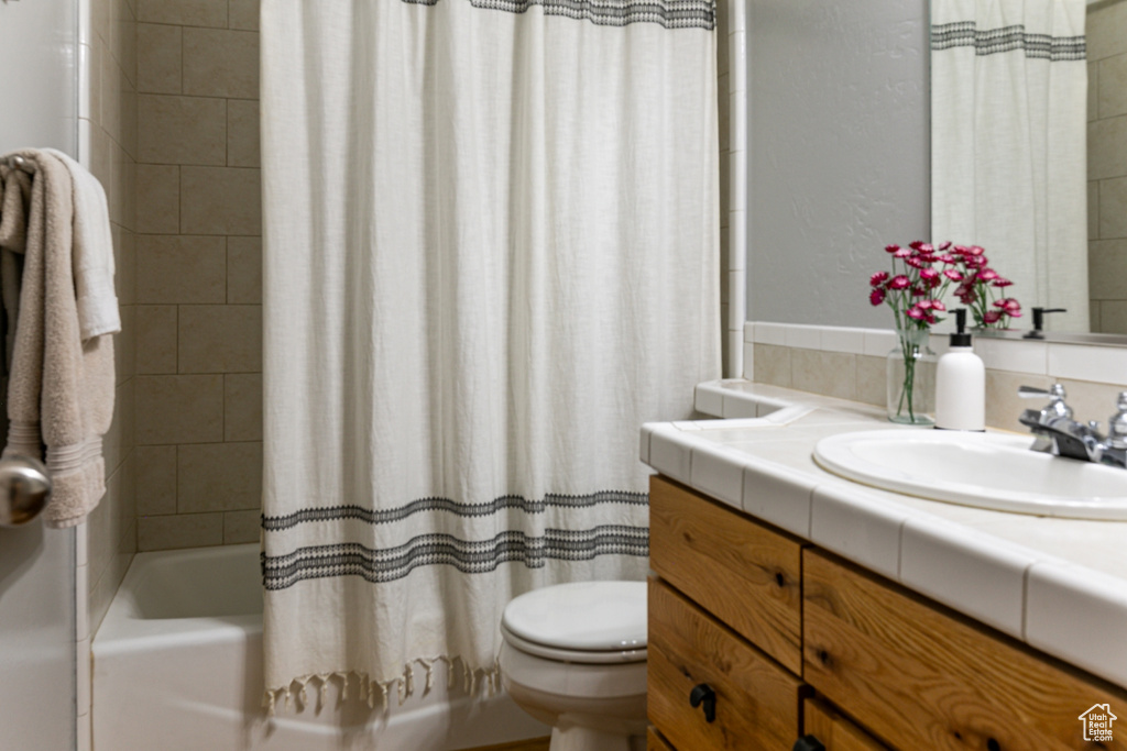 Full bath featuring vanity, shower / bath combo, toilet, and tasteful backsplash