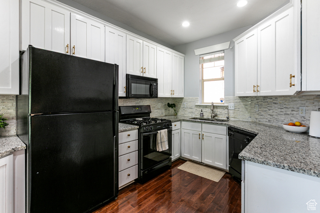 Kitchen featuring black appliances, a sink, dark wood finished floors, white cabinetry, and recessed lighting
