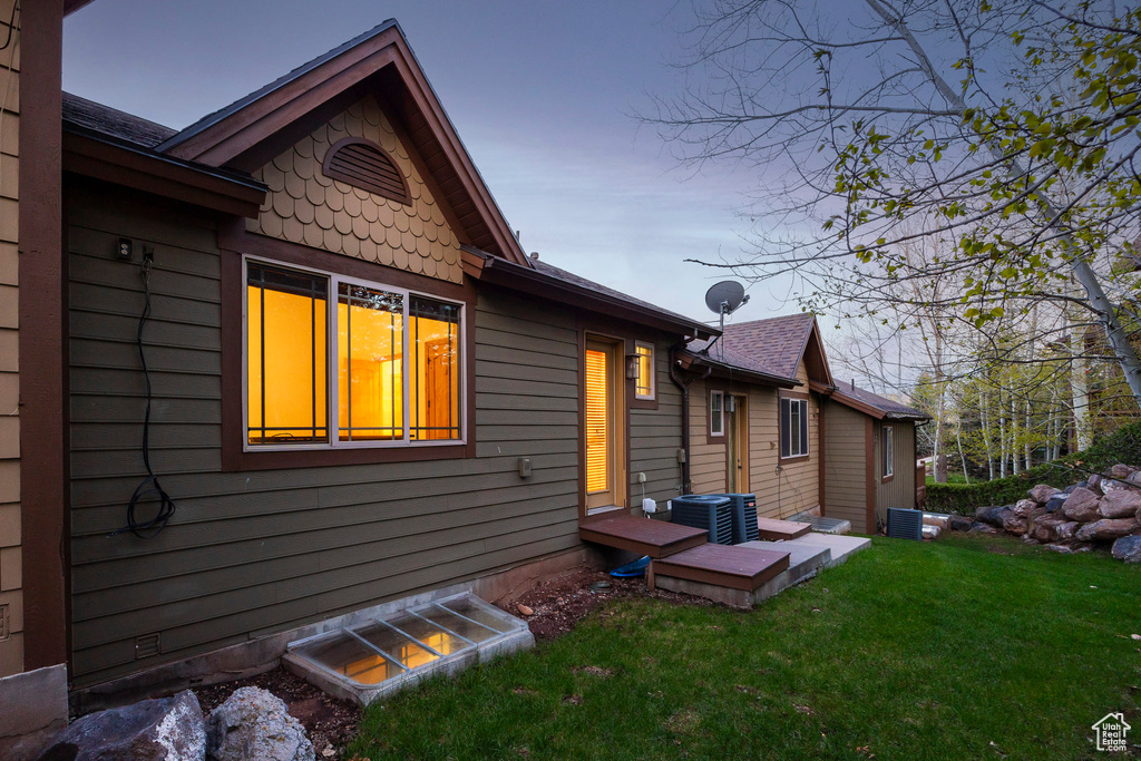Rear view of house with a lawn and central AC unit