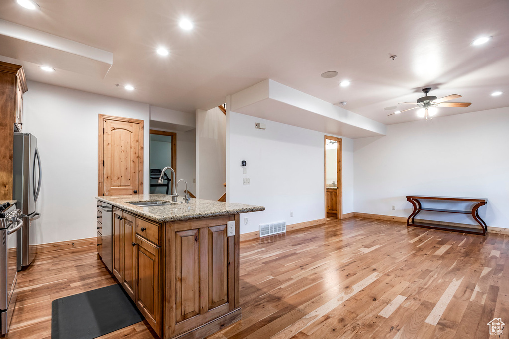 Kitchen featuring a sink, stainless steel appliances, recessed lighting, a kitchen island with sink, and light wood-type flooring