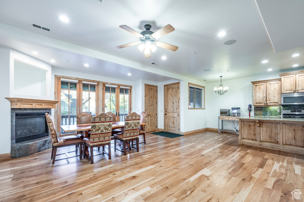 Dining space with a chandelier, light wood-style floors, a fireplace, baseboards, and recessed lighting