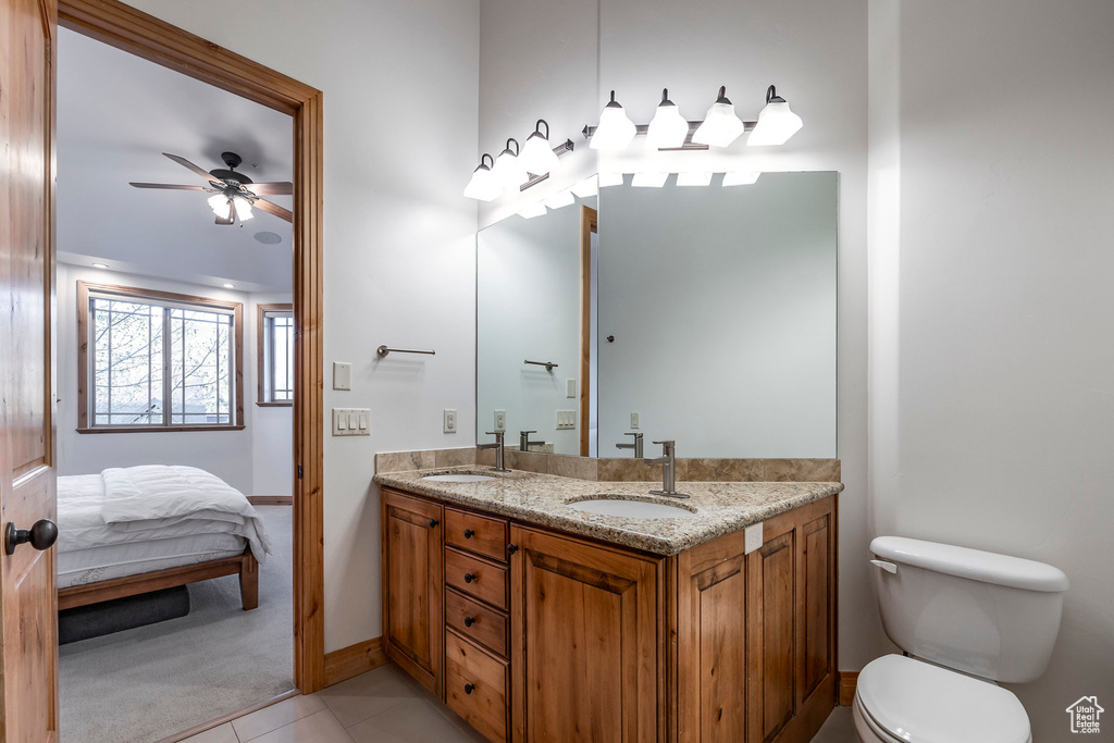 Full bathroom featuring connected bathroom, double vanity, toilet, a ceiling fan, and tile patterned floors
