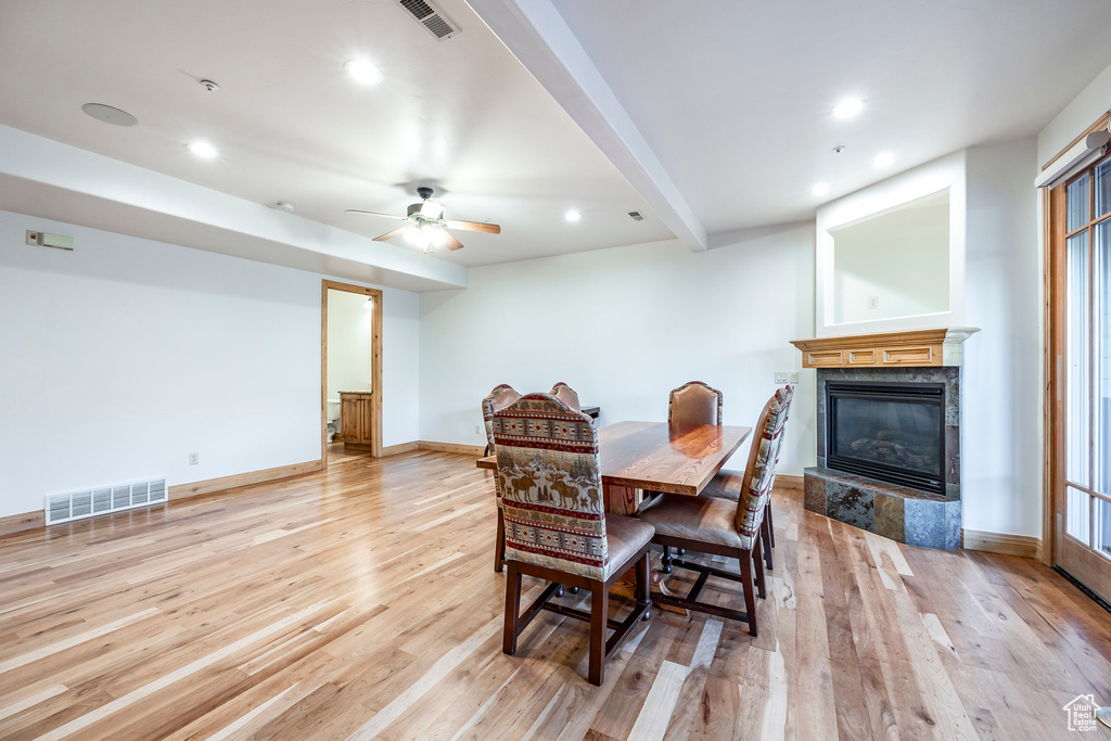 Dining area featuring light wood-type flooring, a premium fireplace, recessed lighting, baseboards, and ceiling fan