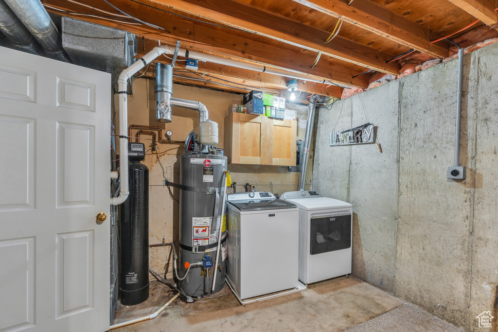 Laundry room featuring water heater, separate washer and dryer, and cabinet space