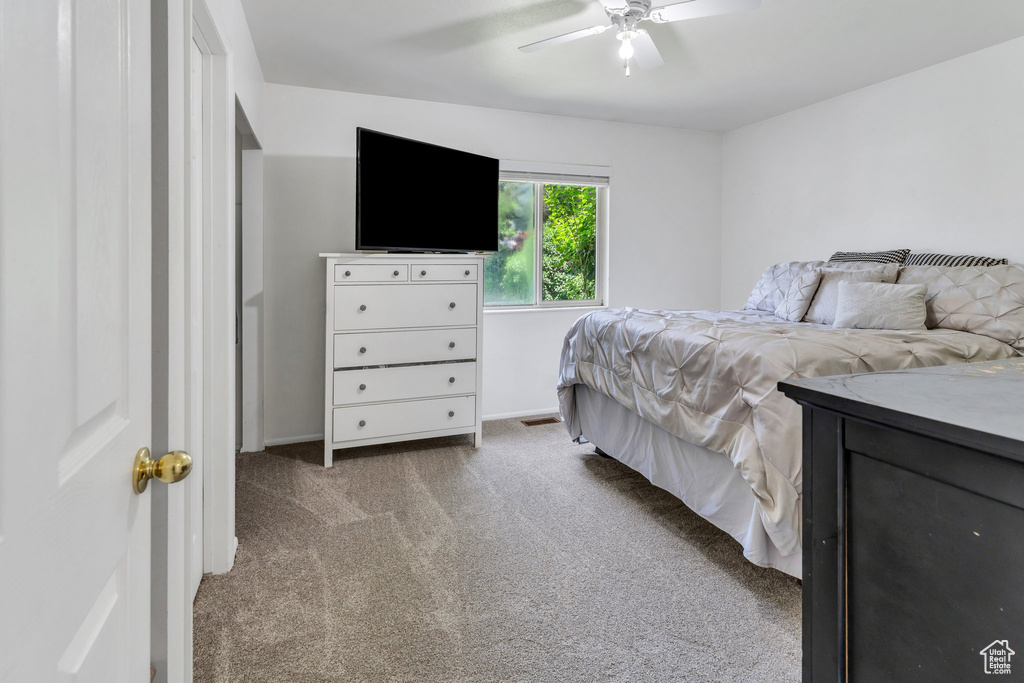 Carpeted bedroom with a ceiling fan and baseboards