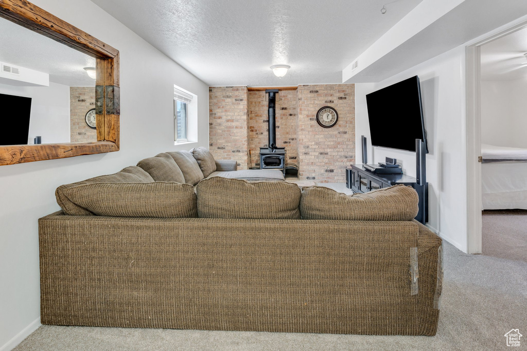 Carpeted living area with a wood stove and a textured ceiling
