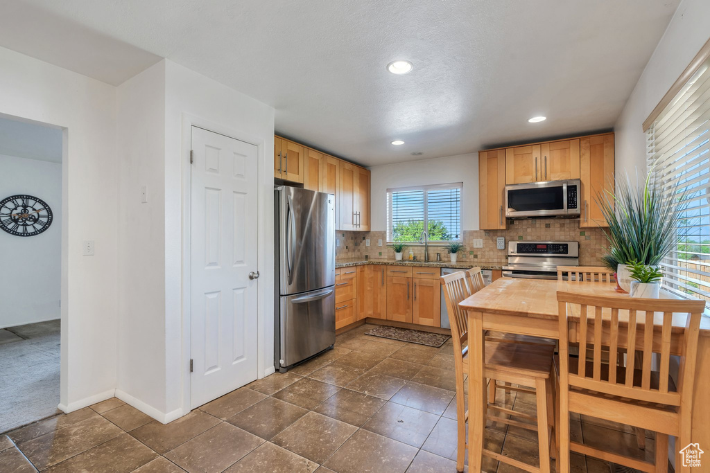Kitchen with appliances with stainless steel finishes, a sink, tasteful backsplash, light brown cabinets, and recessed lighting
