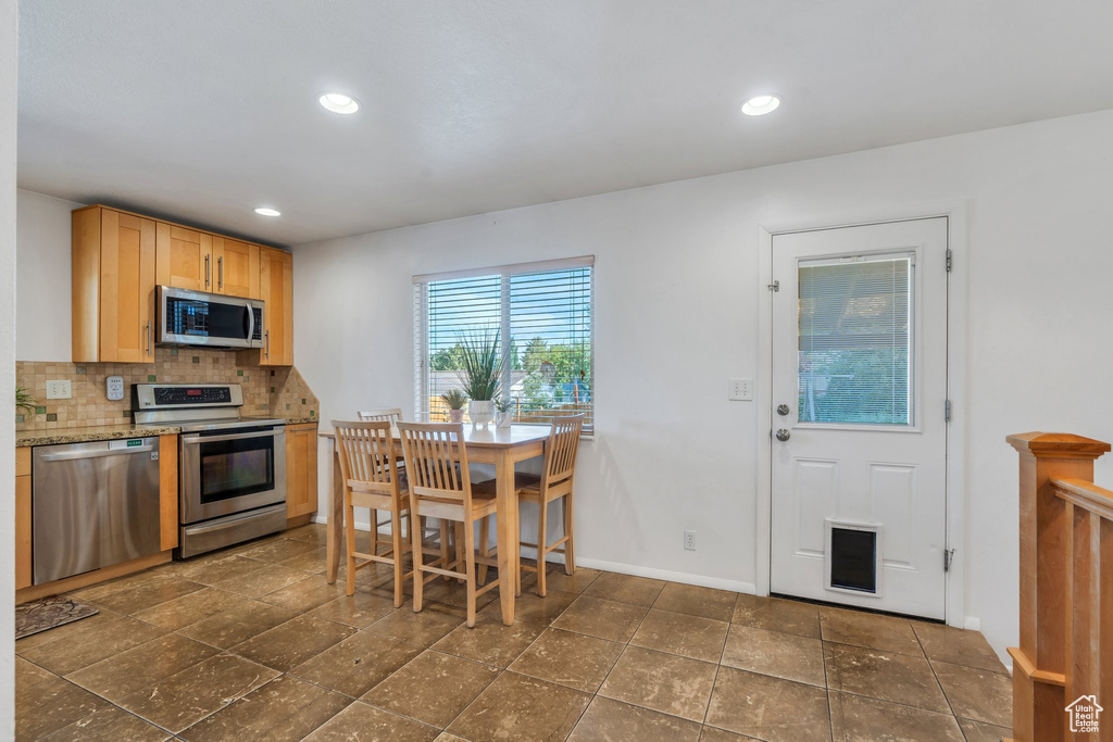 Kitchen featuring stainless steel appliances, backsplash, baseboards, recessed lighting, and light brown cabinetry