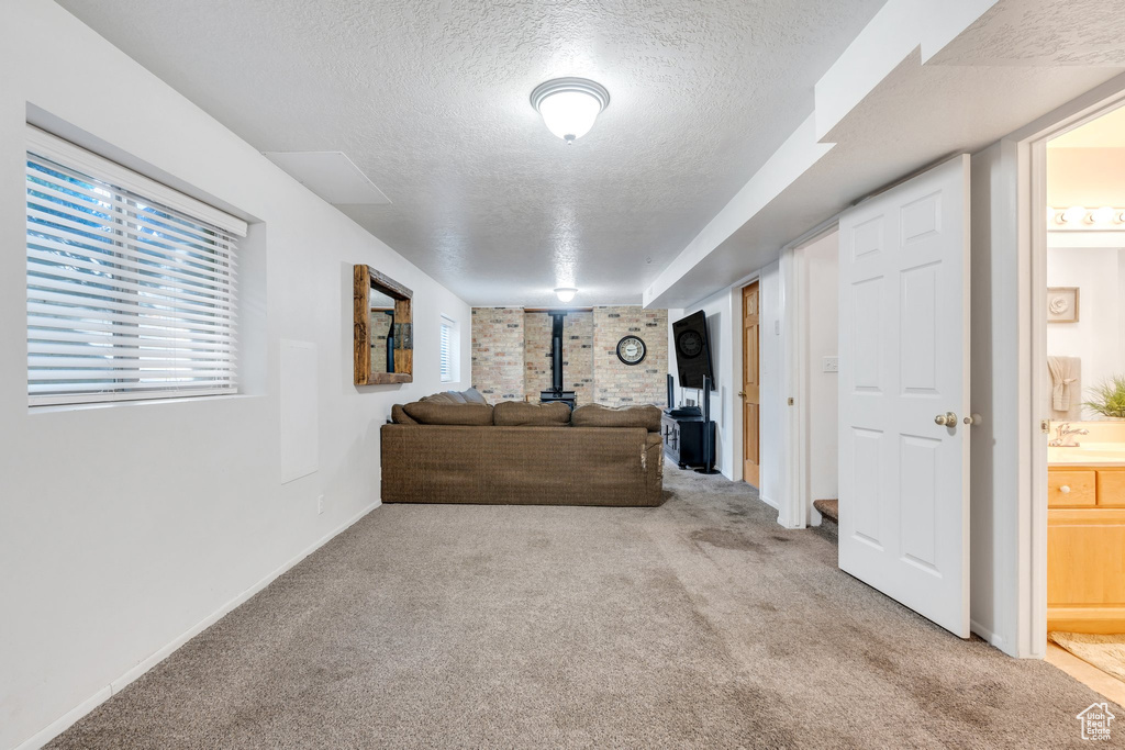 Living room with a wood stove, a textured ceiling, carpet flooring, and baseboards