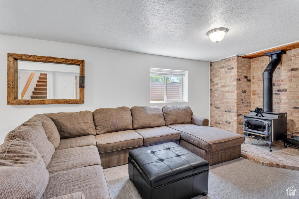 Living area featuring a wood stove, carpet, and a textured ceiling