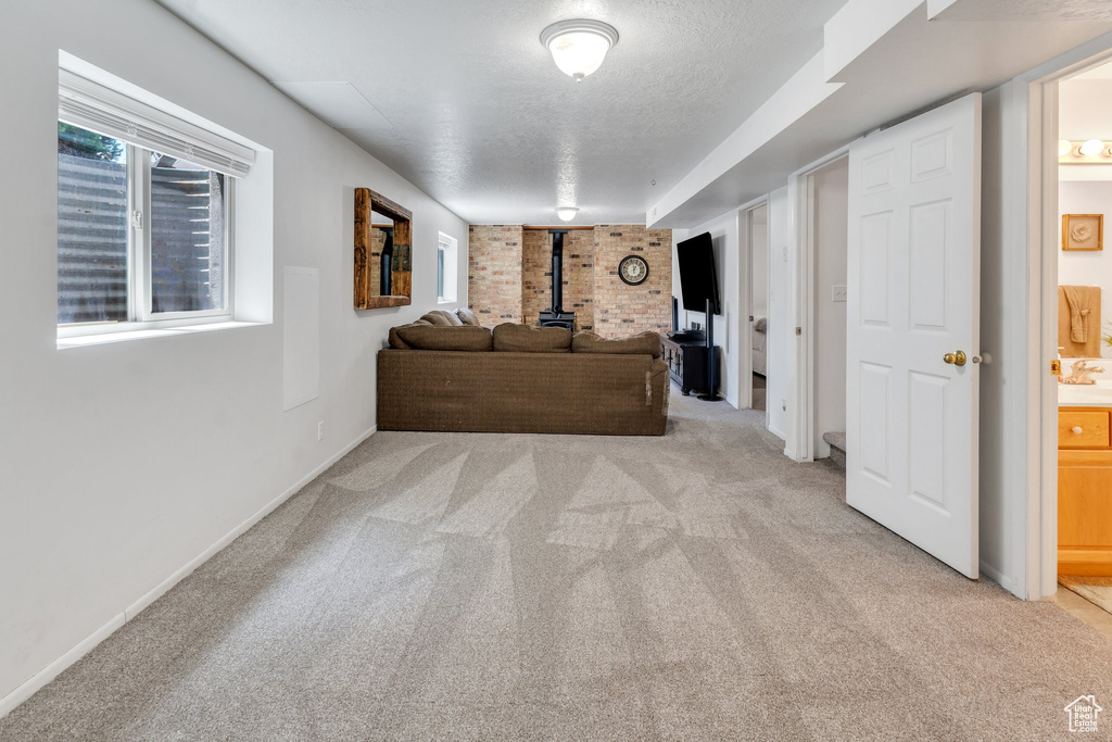 Living room with a wood stove, light colored carpet, a textured ceiling, and baseboards