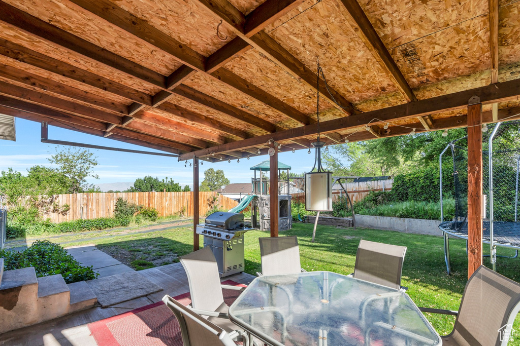 View of patio / terrace featuring a trampoline, grilling area, a playground, and outdoor dining area