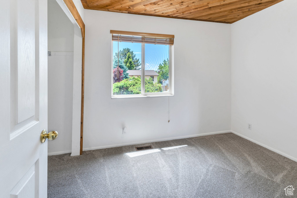 Unfurnished bedroom with wood ceiling, carpet, and baseboards