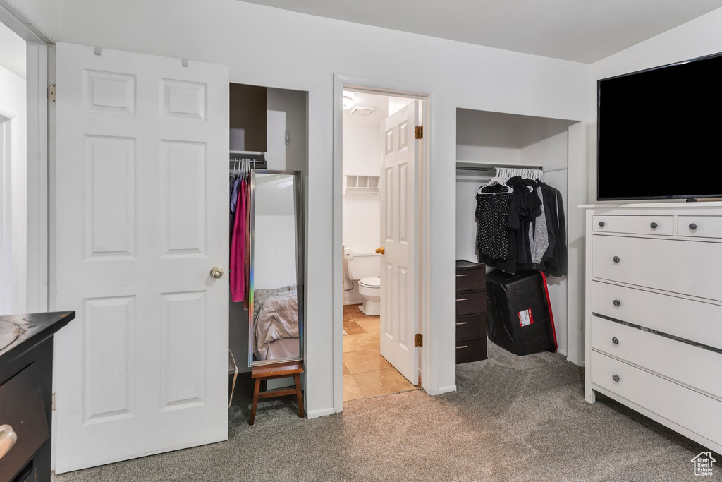 Bedroom featuring light colored carpet, a closet, a spacious closet, and ensuite bath