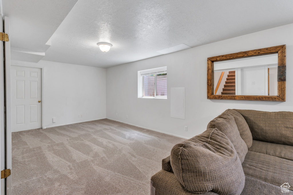 Carpeted living area featuring a textured ceiling and baseboards