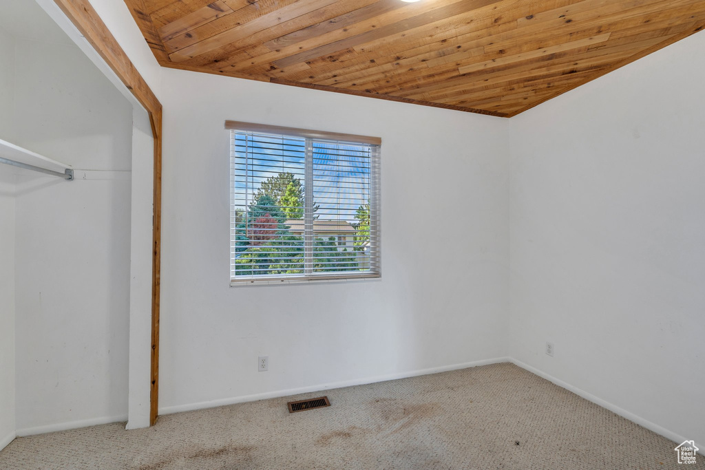 Unfurnished bedroom with carpet floors, baseboards, wooden ceiling, and a closet