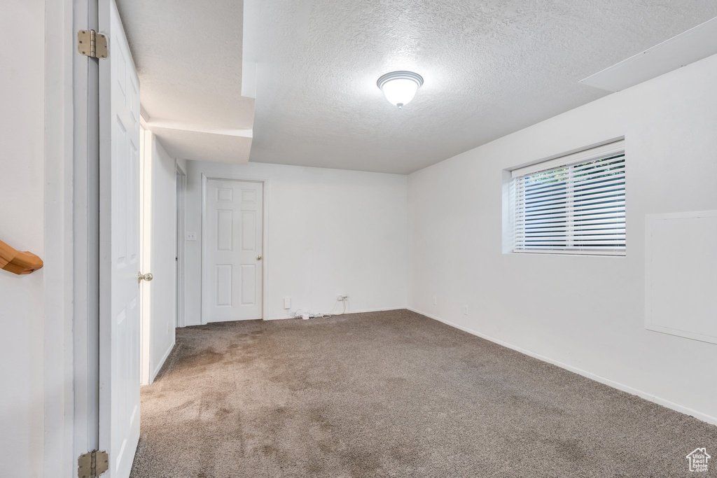 Carpeted empty room with a textured ceiling and baseboards